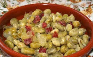 Broad bean salad with chunks of ham and vegetables in a red bowl